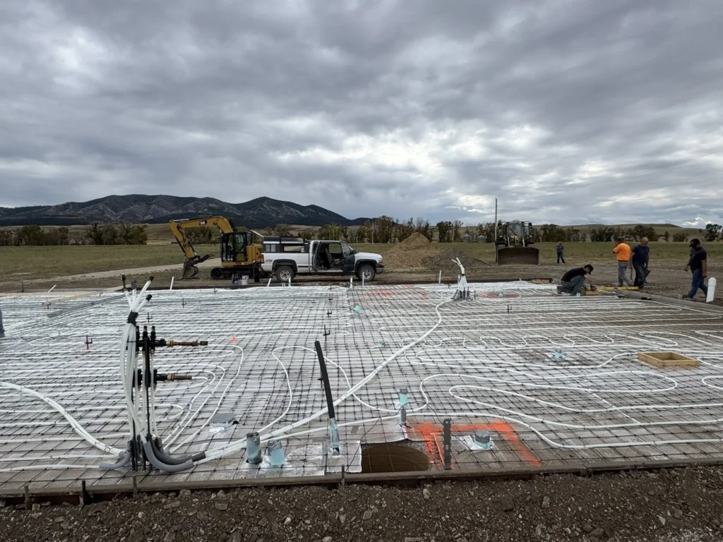 Commercial construction crew installing rebar and in-floor heating lines before pouring a structural concrete slab