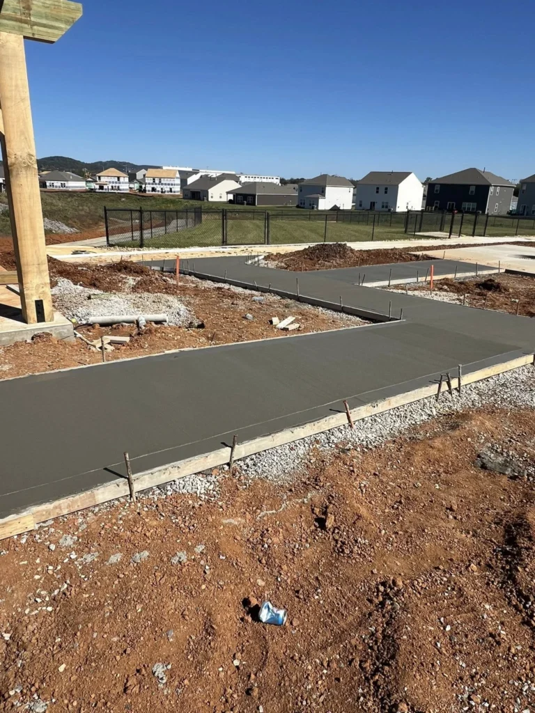 Freshly poured concrete sidewalks with wood formwork on a commercial construction site.