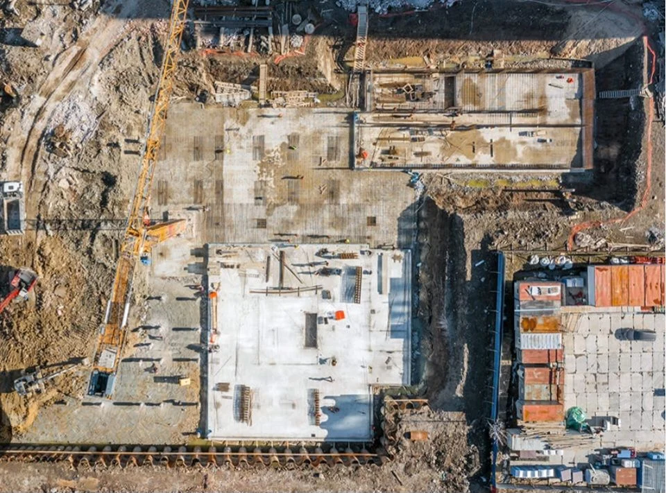 Aerial view of a large commercial concrete construction site with foundation slabs and heavy equipment