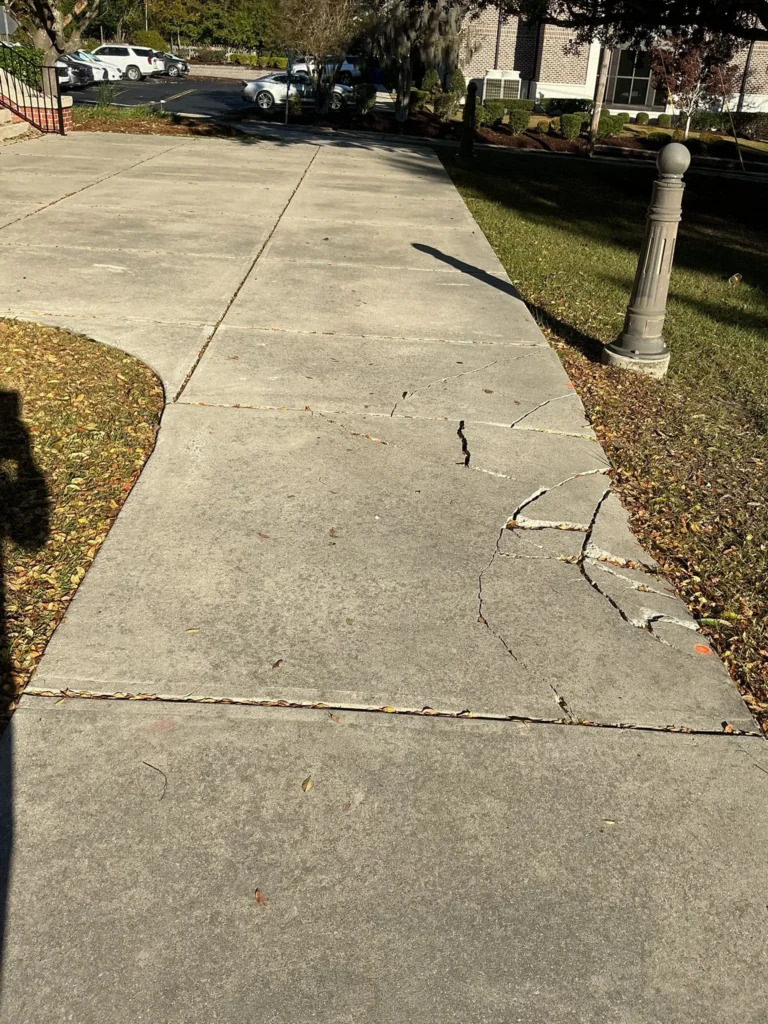 Damaged concrete sidewalk before repair showing cracks and settlement, part of concrete sidewalk & walkway services in Edmonton