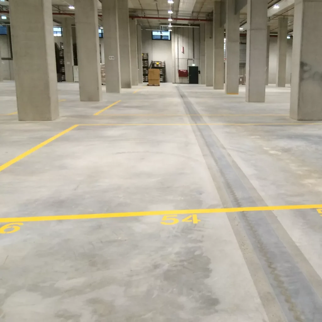 Industrial concrete warehouse floor in Edmonton with smooth slab, control joints, and marked traffic lanes for forklift operations