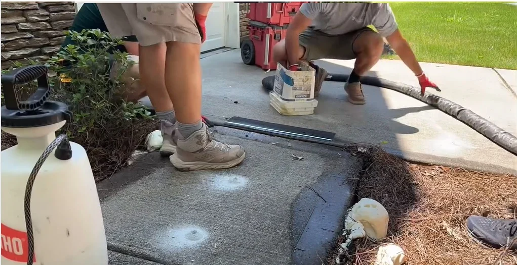 concrete lifting Edmonton showing mudjacking injection holes drilled in sunken driveway slab
